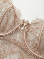 Close-up of a nude lace underwire bra cup and neckline. Features sheer beige floral lace, luxurious satin underwire casing, delicate eyelash lace trim, and a dainty satin center bow for elegant women's lingerie.