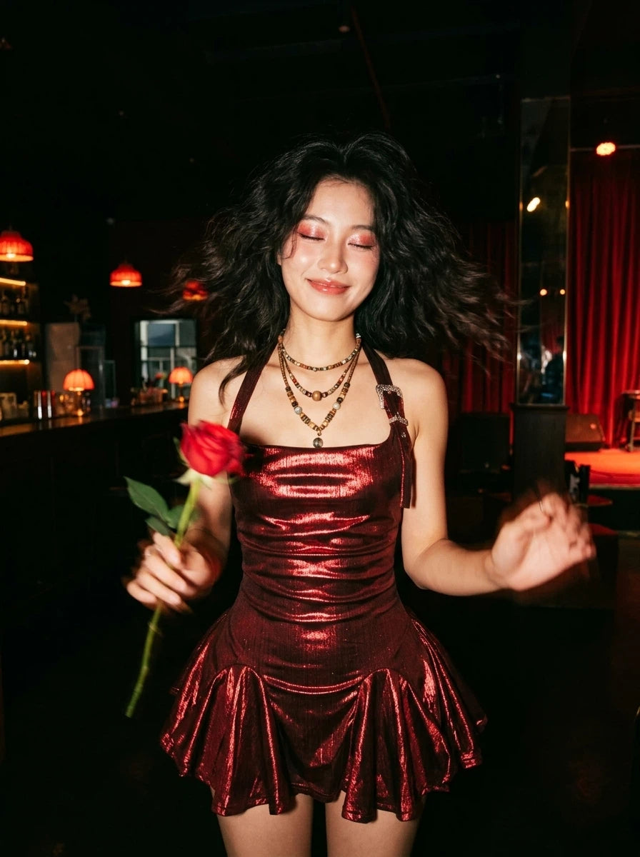 Striking metallic red halter mini dress featuring a flattering ruched bodice and a flared skirt. This Y2K-inspired avant-garde clubwear includes a unique vintage-style engraved buckle strap, perfect for statement festival fashion or bold party outfits.