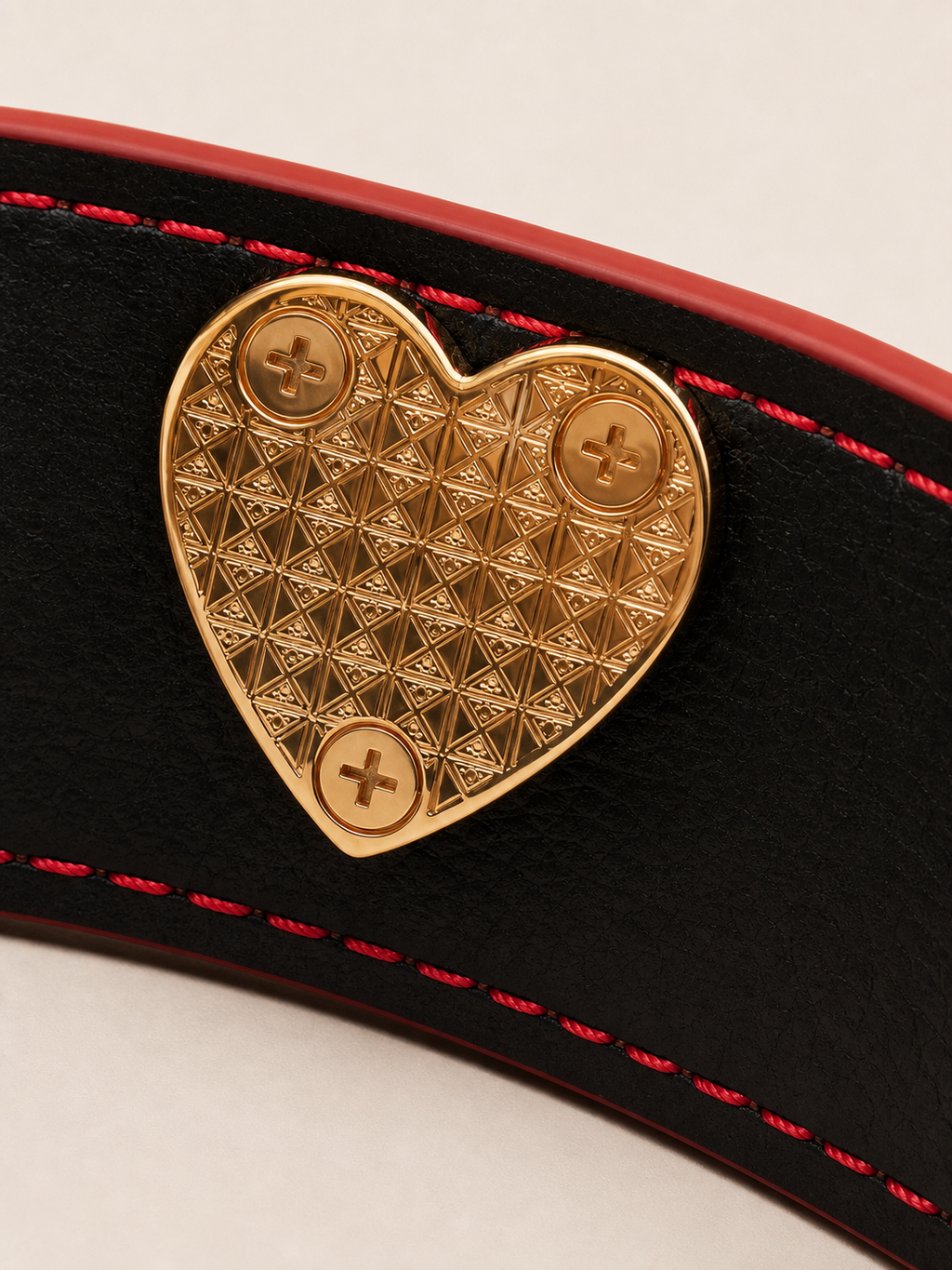 Detailed view of the interior geometric heart plate on the Velvet Fluxe luxury leather cuff. Features precision craftsmanship and high-end gold-tone hardware for a refined boudoir experience.
