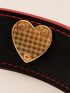 Detailed view of the interior geometric heart plate on the Velvet Fluxe luxury leather cuff. Features precision craftsmanship and high-end gold-tone hardware for a refined boudoir experience.