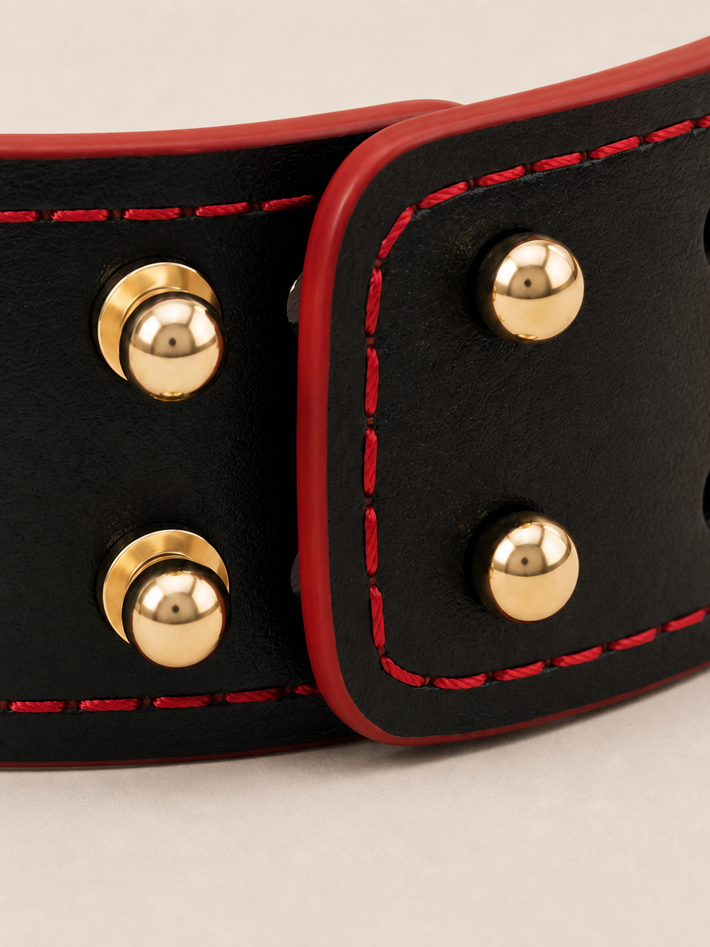 Detail of the adjustable multi-stud closure on the Velvet Fluxe black leather cuff, highlighted by vibrant crimson red contrast stitching. Designed for a custom, secure fit for wrists or ankles.