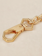 Close-up of the custom hexagonal gold snap-hook clasp on the Velvet Fluxe detachable chain. Showcasing the intricate hardware design of our luxury intimate restraint accessories.