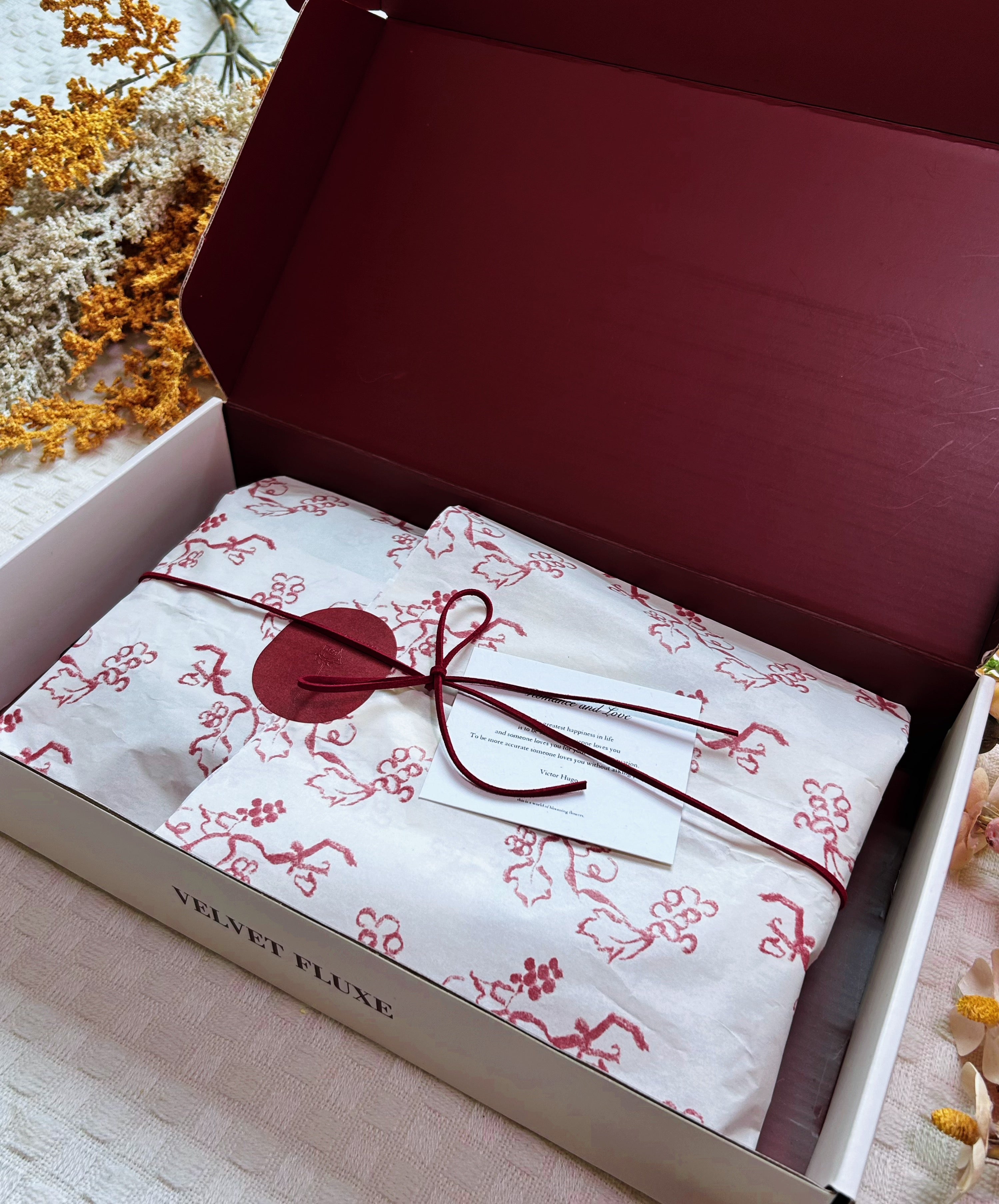 Velvet Fluxe deep burgundy luxury gift box opened revealing custom floral tissue paper, wine red suede cord, simulated wax seal sticker, and scented card poetry card, luxury lingerie unboxing ritual