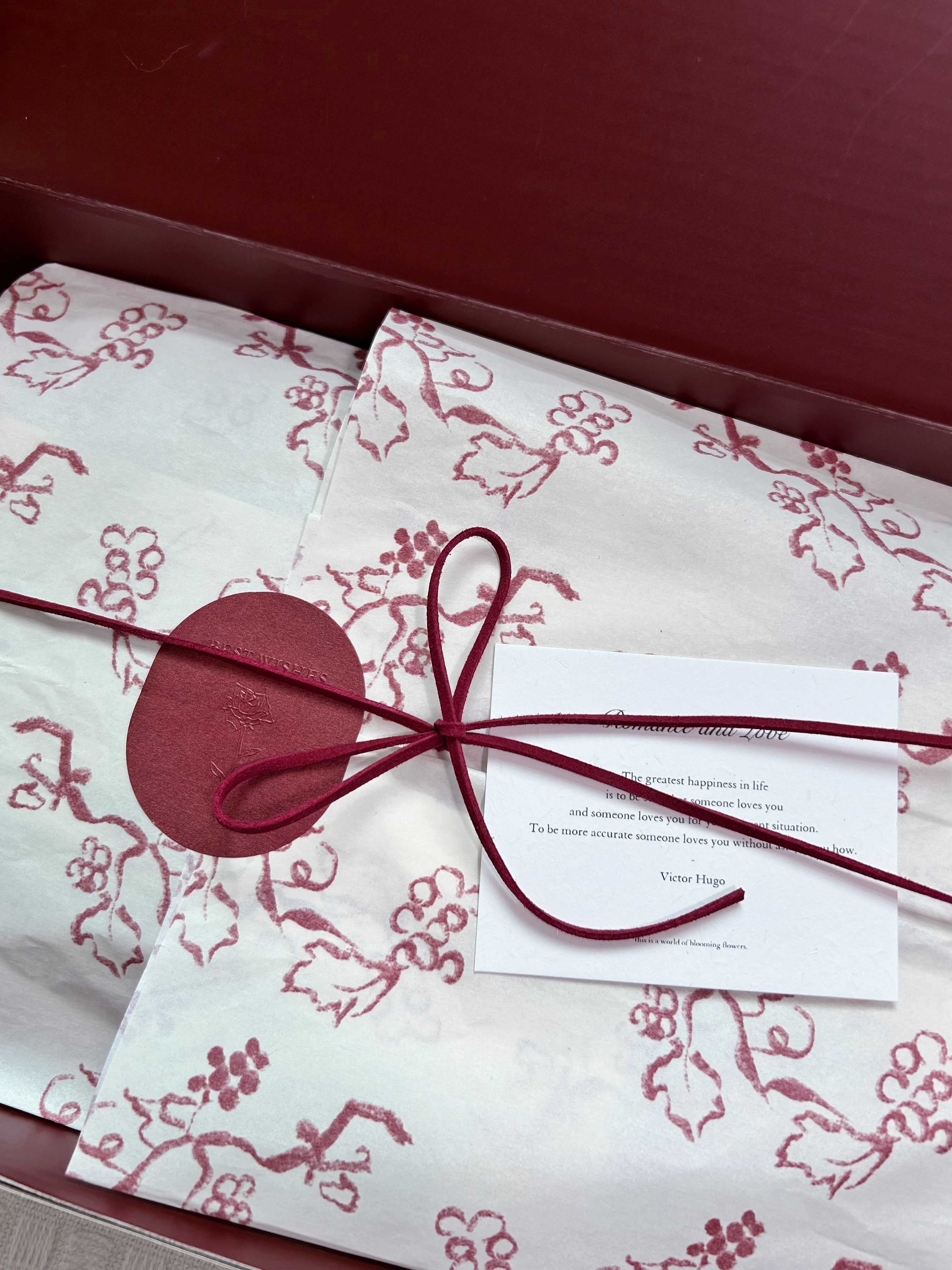 Velvet Fluxe deep burgundy luxury gift box opened revealing custom floral tissue paper, wine red suede cord, simulated wax seal sticker, and scented card poetry card, luxury lingerie unboxing ritual