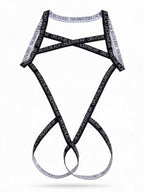 Flat lay product view of the black graphic letter men's body harness, detailing the strap structure and bold text pattern on a clean background.