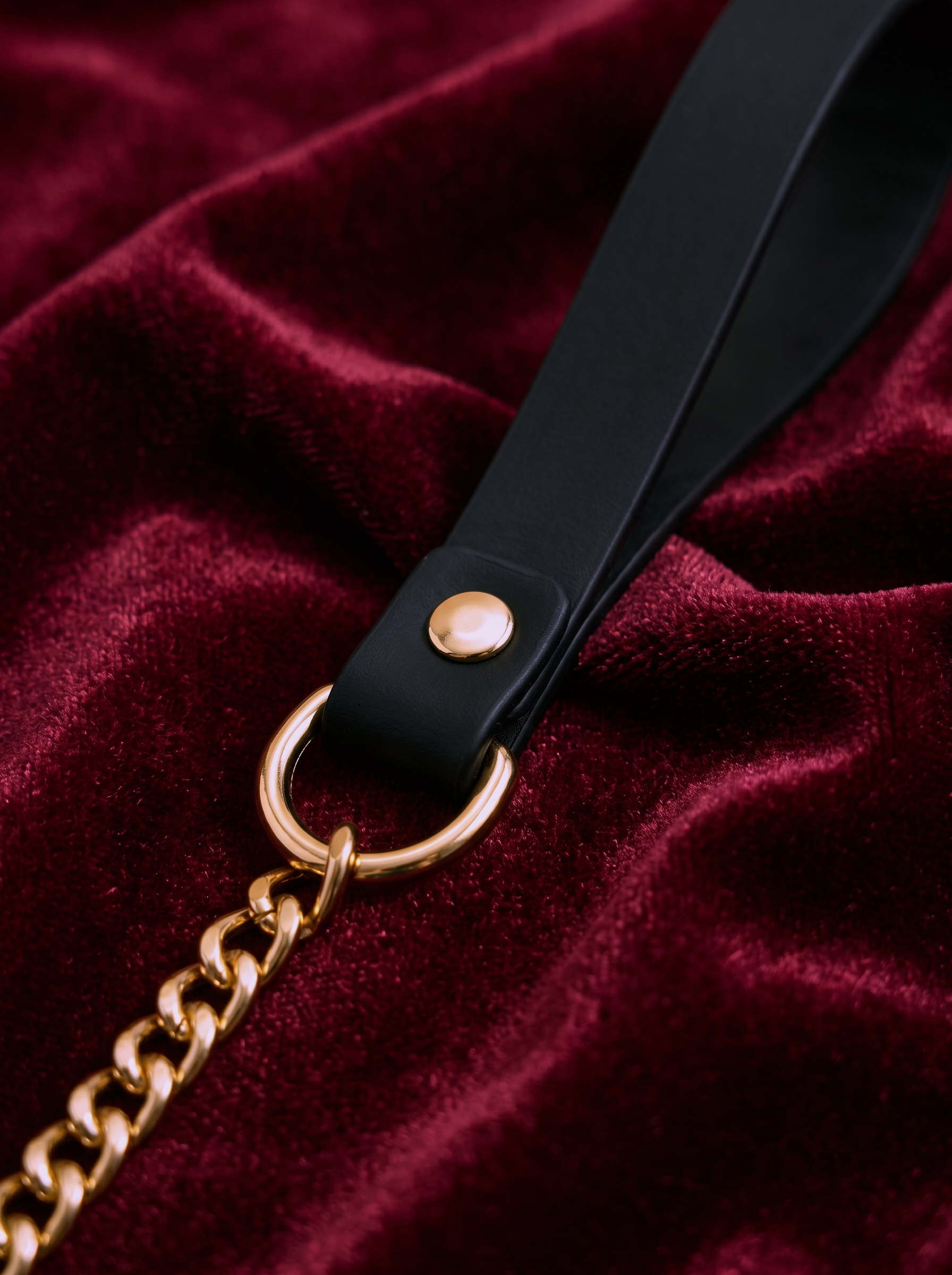 Detailed view of the sleek black vegan leather handle attached to a heavy-duty gold chain leash via a polished O-ring. Part of the Velvet Fluxe KIRA collar set, designed for sophisticated power dynamics and romantic roleplay.