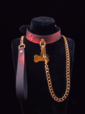 The Velvet Fluxe KIRA collar reacting to heat, turning a blushing pink with embossed sakura details. Shown on a black mannequin with a luxury gold chain leash and bone tag. Perfect for dark coquette aesthetics and high-end sensual play.