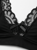 Close up of Velvet Fluxe NOCTURNE French men's black lace bralette. Product shot highlighting the sheer floral lace triangle cups, scalloped edging, center bow detail, and adjustable straps on a pure white background.