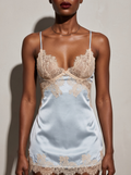 Model wearing the Velvet Fluxe Céleste ice blue satin and lace chemise. Front view emphasizing the plunging sheer champagne lace cups and luxurious silky drape in dramatic boudoir lighting.