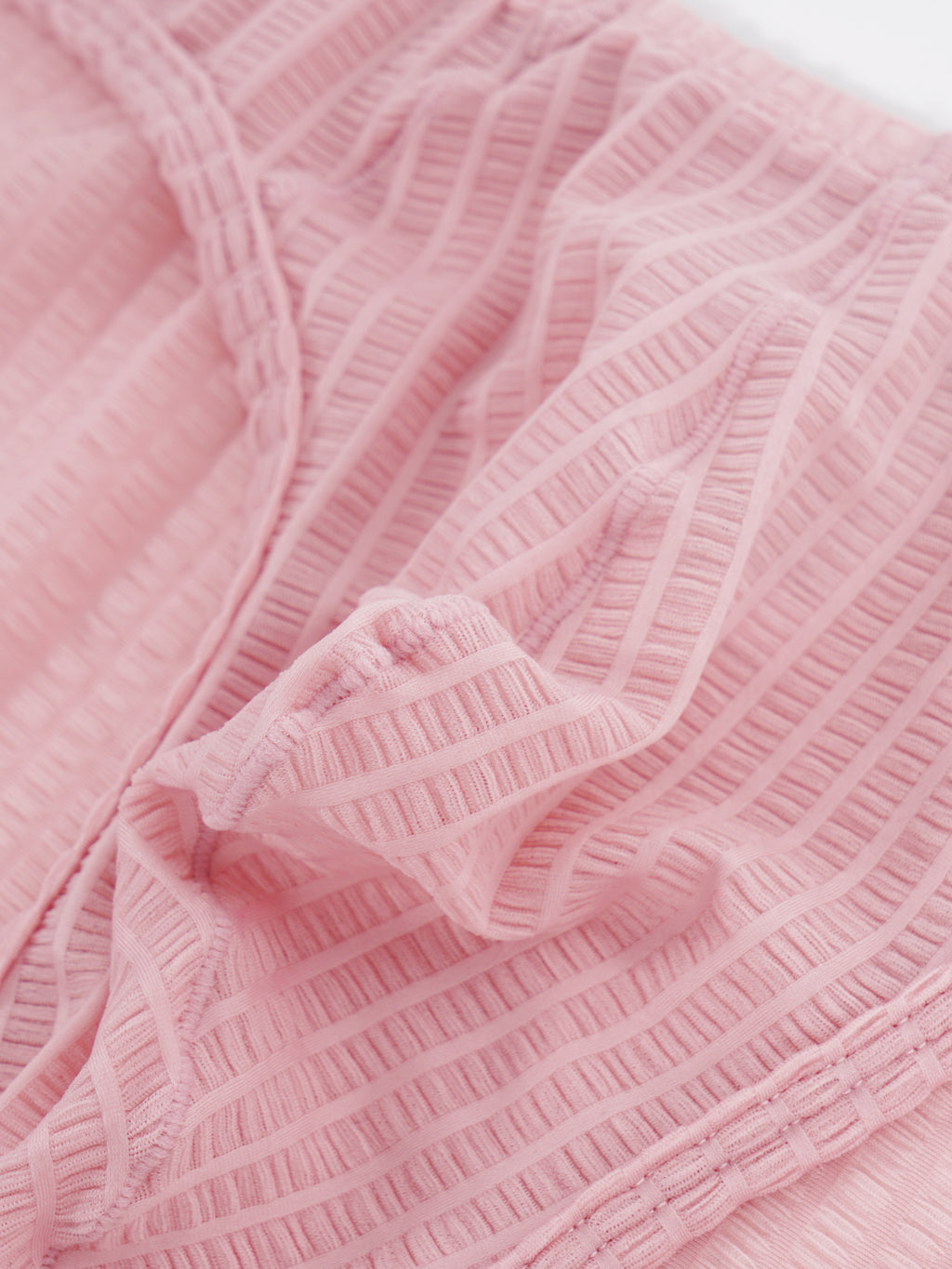 Close-up fabric detail of Velvet Fluxe DOMEUP men's briefs in pink, showing the reflective 3D ribbed texture woven from mercerized nylon and spandex.