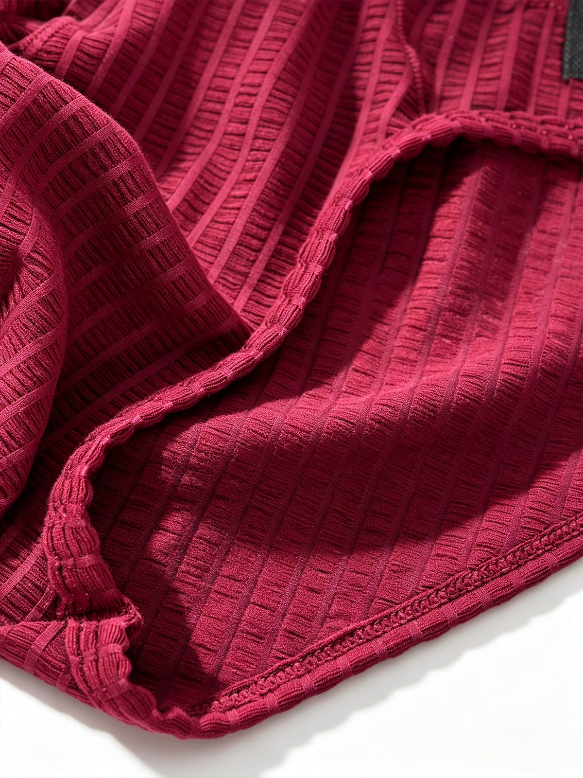 Macro fabric shot of Velvet Fluxe DOMEUP men's briefs in red, highlighting the intricate warp-and-weft weaving and heartbeat-inducing sheer texture.